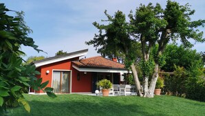 A red house with a tiled roof, a front porch, and a well-maintained lawn. - Very nice 'villetta' in beautiful and quiet fully garden. (Bardolino)