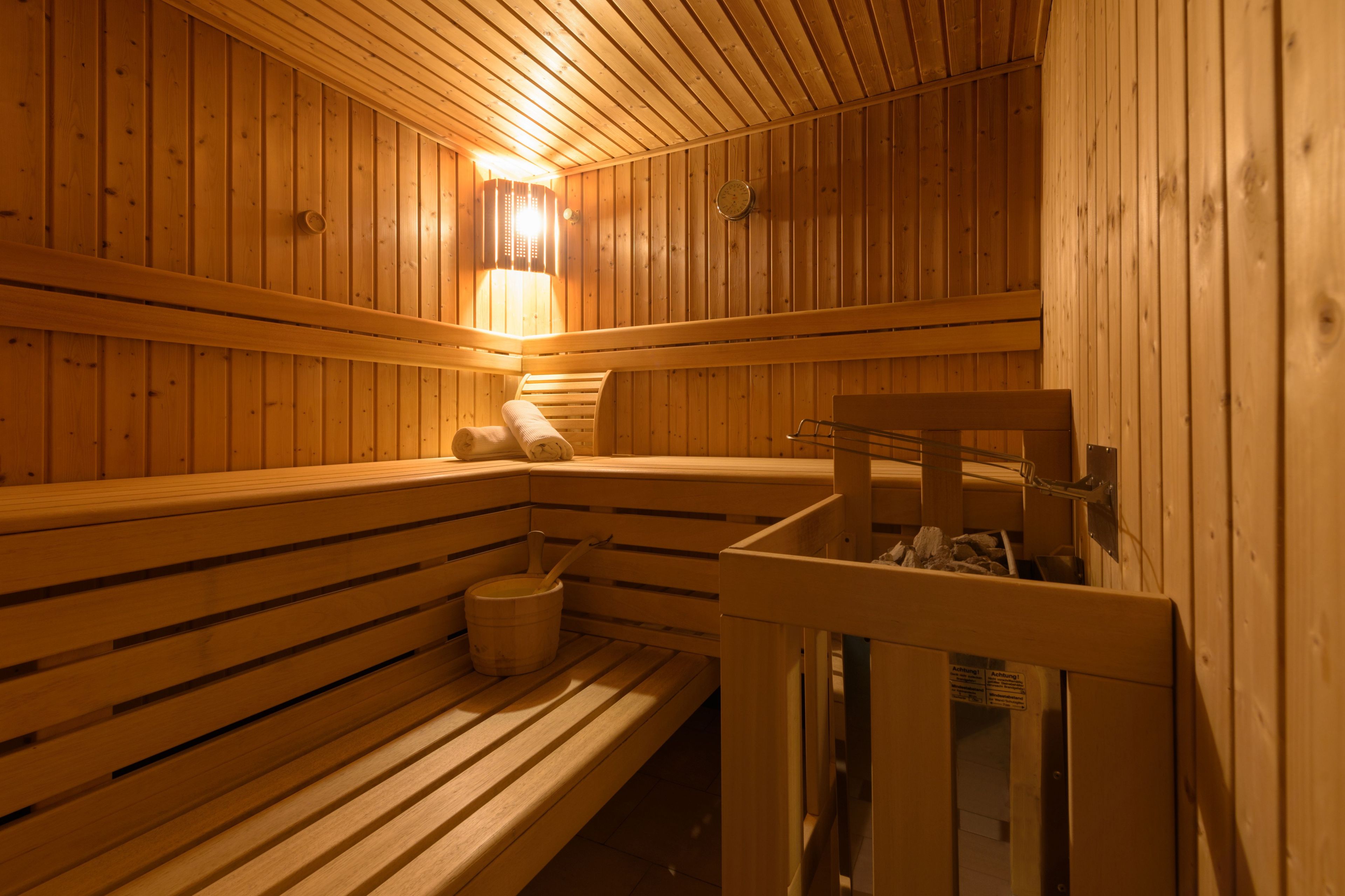 A wooden sauna with benches and a bench with a towel and bucket.
