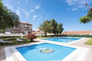 A swimming pool with a sun design, surrounded by lounge chairs and palm trees. - Home2Book Beautiful Apart Los Cristianos Pool Wifi (Arona)