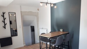 Ein moderner Essbereich mit einem Holztisch, zwei Stühlen, einem Spiegel an der Wand und einer Deckenleuchte.