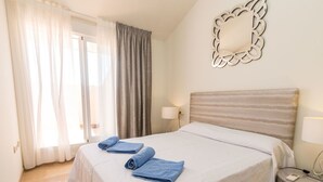 Ein Hotelzimmer mit Bett, Nachttisch, Lampe und einem Zier-Spiegel.