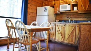 Une cuisine de style rustique, avec des meubles en bois, un réfrigérateur, un four à micro-ondes et une table à manger avec des chaises.