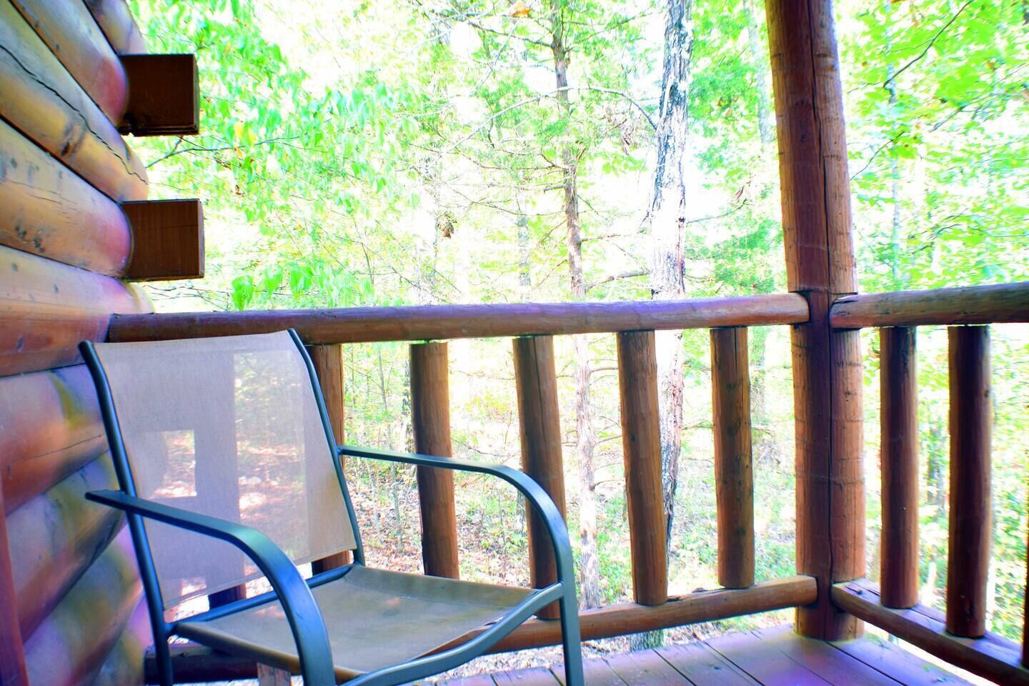 A wooden deck with a metal chair and a wooden railing.