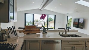 A modern kitchen with a large island, stainless steel appliances, and a view of the outdoors.