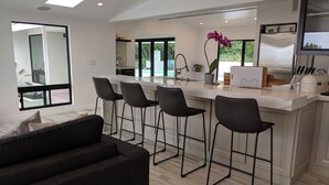 A modern kitchen with a bar area, large windows, and a view of the outdoors.