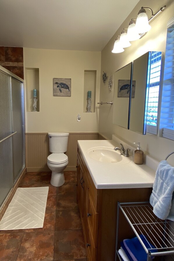 Une salle de bain avec des toilettes, un lavabo et un miroir. On y trouve des éléments décoratifs sur le mur et un porte-serviettes.
