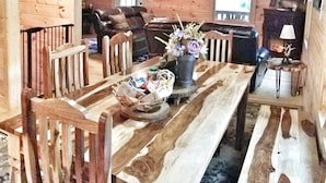 Een houten interieur met een eettafel, stoelen, een bank en een televisie.