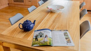 A wooden dining table with a blue teapot, a bowl, and an open magazine. - 140 m² apartment surrounded by nature (Puchberg am Schneeberg)