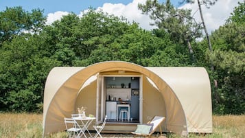 Un espacio exterior cubierto con cocina, juego de comedor y sillón de descanso.