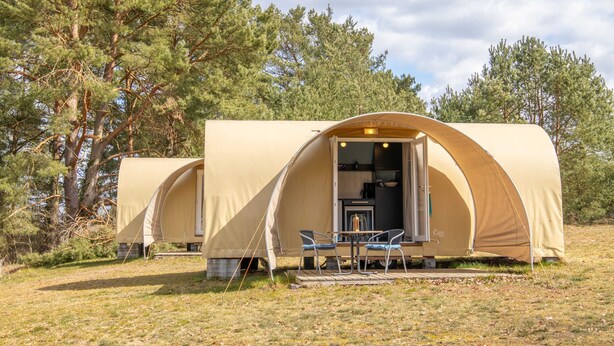 Tenda com dois ambientes, área de refeições e pequena cozinha.