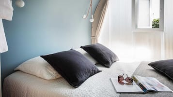 Un dormitorio con dos camas, una ventana con cortinas y una revista sobre la cama.