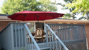 A covered outdoor area with a red umbrella, a staircase, and a table with chairs. - About Legacy House @ Concord (Smyrna)