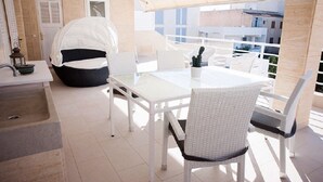 A balcony with a white table and chairs, a cushioned chair, and a potted cactus. - A very special apartment for up to 5 people. (Colònia de Sant Jordi)