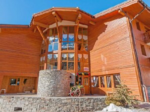 A wooden chalet with a stone base, large windows, and a wooden porch. - Spacious Duplex Apartment for 10-12 near Val-Cenis Slopes with Balcony & Free Wifi (Lanslevillard)
