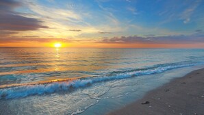 Une plage avec un coucher de soleil sur l’océan.