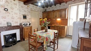 Una cocina acogedora con armarios de madera, una mesa de comedor con mantel floral y un florero con flores.