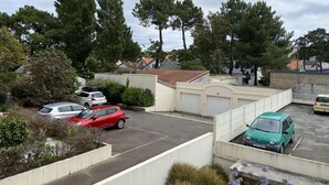 A parking area with several cars, surrounded by trees and buildings.