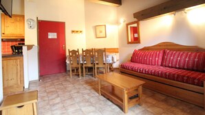 Ein gemütliches Wohnzimmer mit einer Holzsofa, einem Holztisch und einem Essbereich mit Stühlen und einem Tisch.
