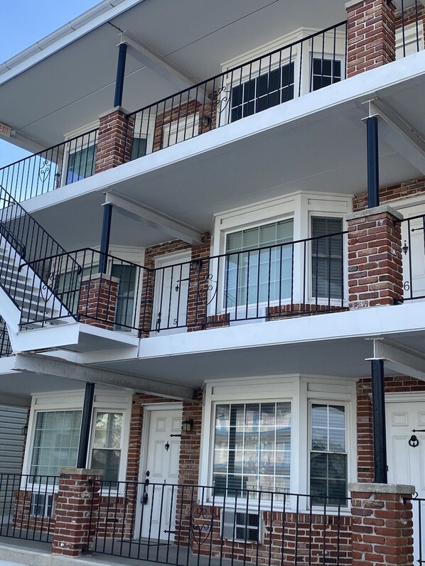 A multi-story residential building with brick facades, white trim, and black railings.