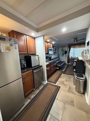 A kitchen with wooden cabinets, stainless steel appliances, and a tiled floor.