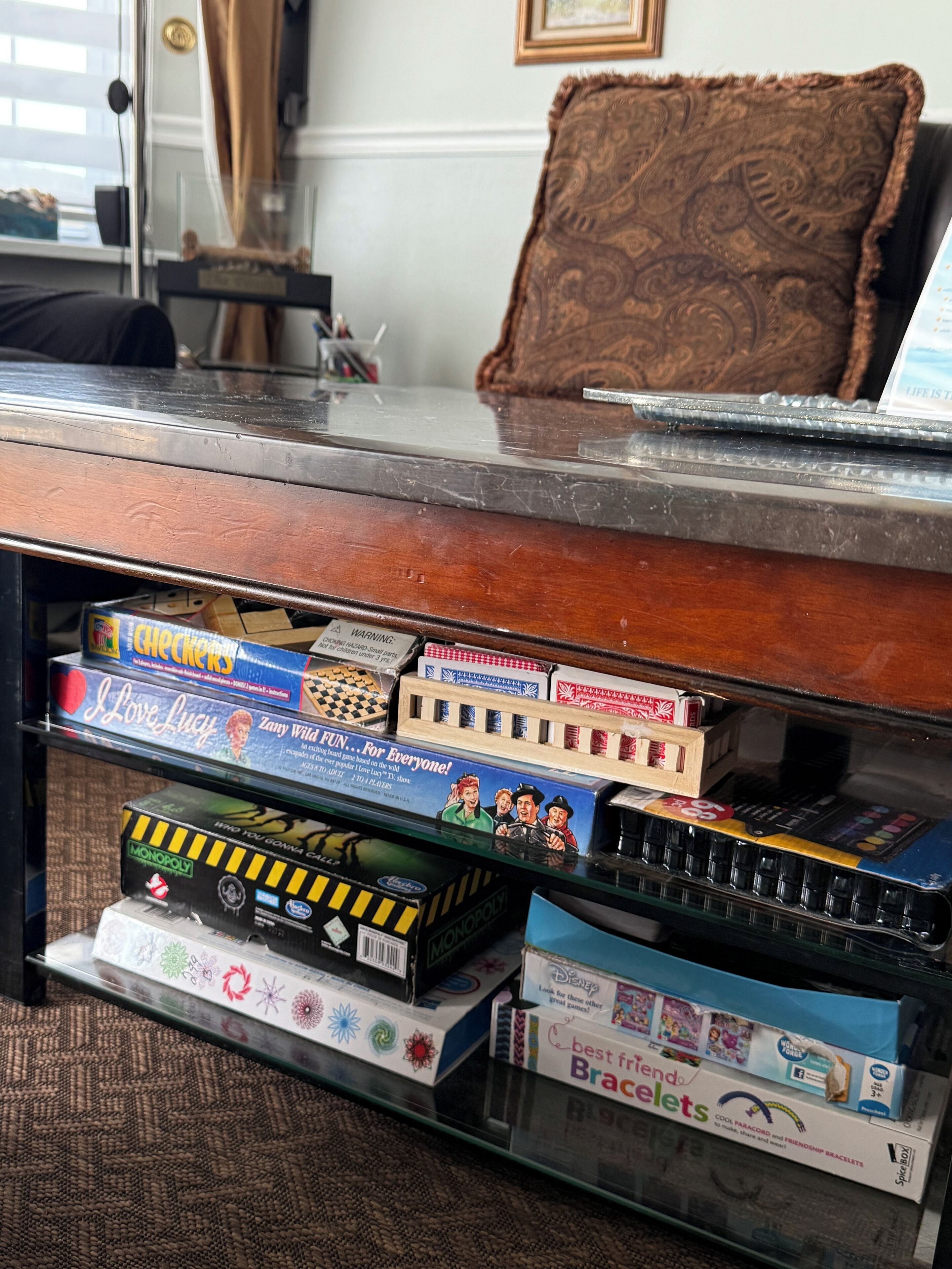 Un escritorio con superficie de vidrio, varios juegos de mesa y una silla.
