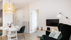 Una sala de estar moderna con comedor, televisión y lámpara.