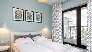 Un dormitorio con dos camas, una ventana con vistas y cuadros en la pared.