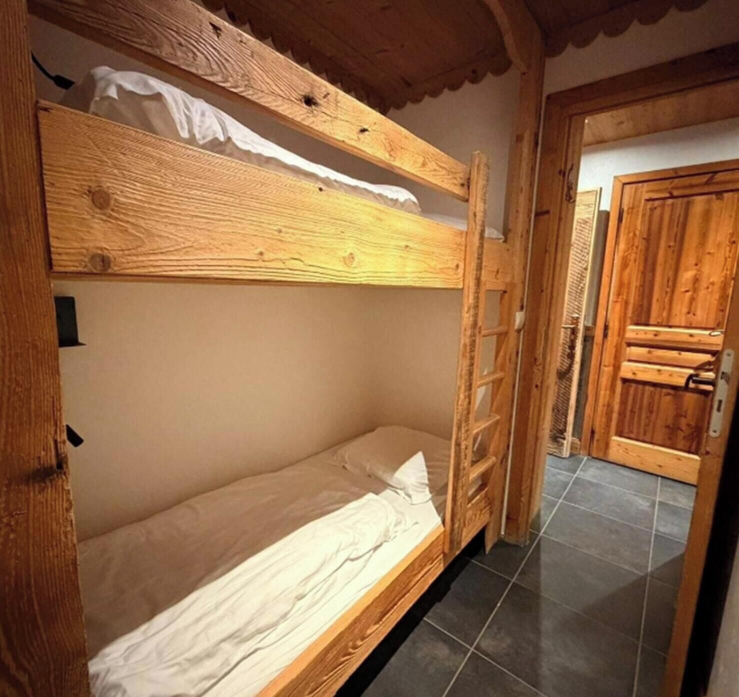 Un lit superposé avec une structure en bois, un matelas blanc et une tête de lit.