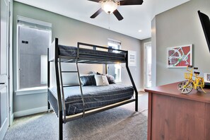 A bunk bed with a desk and chair, a ceiling fan, and a bicycle.