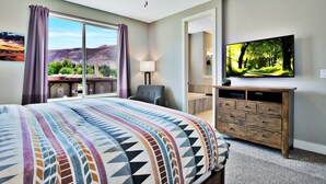 Une chambre d’hôtel avec un grand lit, un bureau, une chaise, une télévision et une vue sur les montagnes.