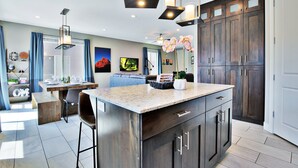 Une cuisine moderne avec des meubles en bois foncé, un plan de travail en granit et des luminaires suspendus.