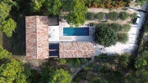 Une vue aérienne d’une maison avec une piscine, entourée d’arbres et d’un jardin.