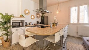 Una cocina moderna con una isla central, sillas blancas, microondas, refrigerador y adornos en la pared.