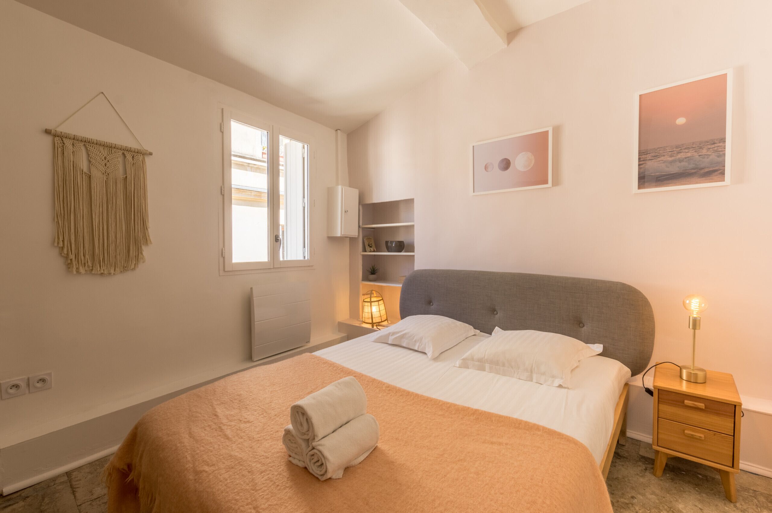 Une chambre à coucher avec un lit, une lampe de chevet et une décoration murale en macramé.