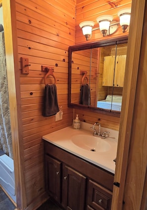 Een bad/douchecombinatie, een haardroger, handdoeken, zeep