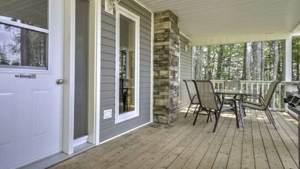 A covered porch with a stone accent wall, a dining table with chairs, and a 'No Smoking' sign on the door.