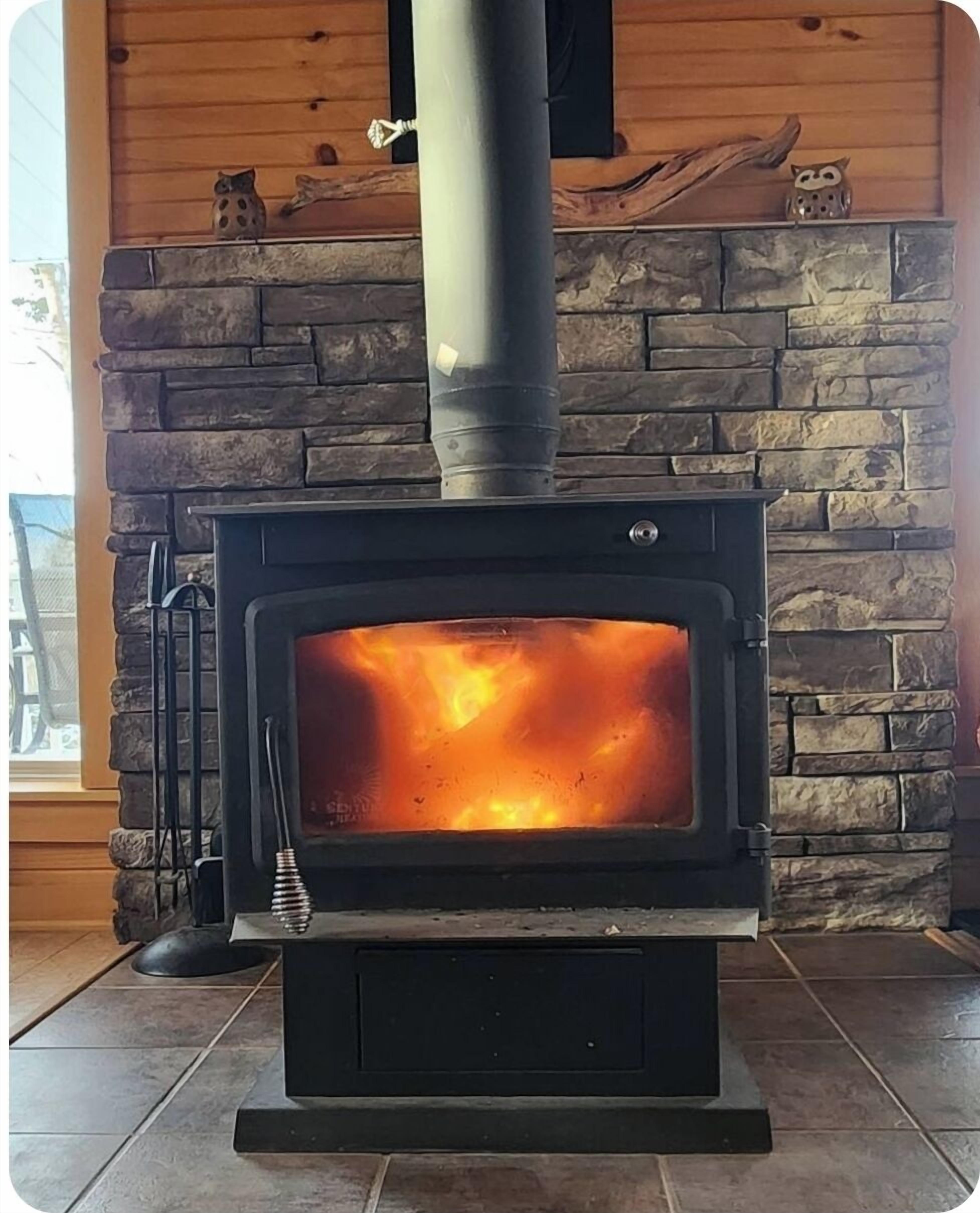 A wood-burning stove with a stone facade and a chimney.