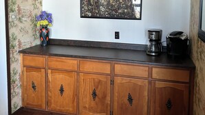Une cuisine avec un meuble en bois, une machine à café et un vase rempli de fleurs.