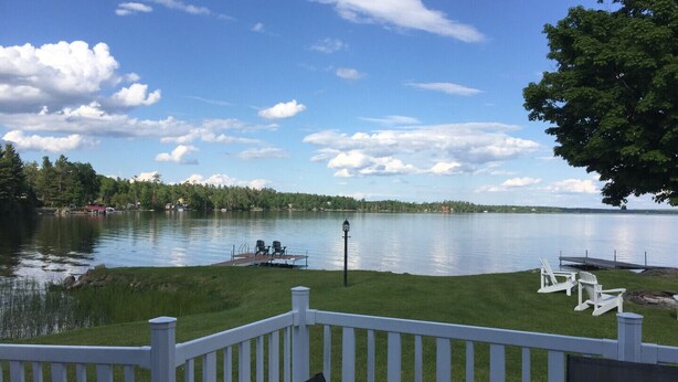 Une vue sur le lac avec un quai, des chaises et une clôture blanche.