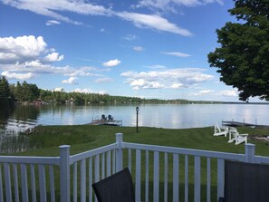 Une vue sur le lac avec un quai, des chaises et une clôture blanche.