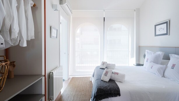 Et hotelværelse med seng, garderobeskab, radiator og udsigt ud