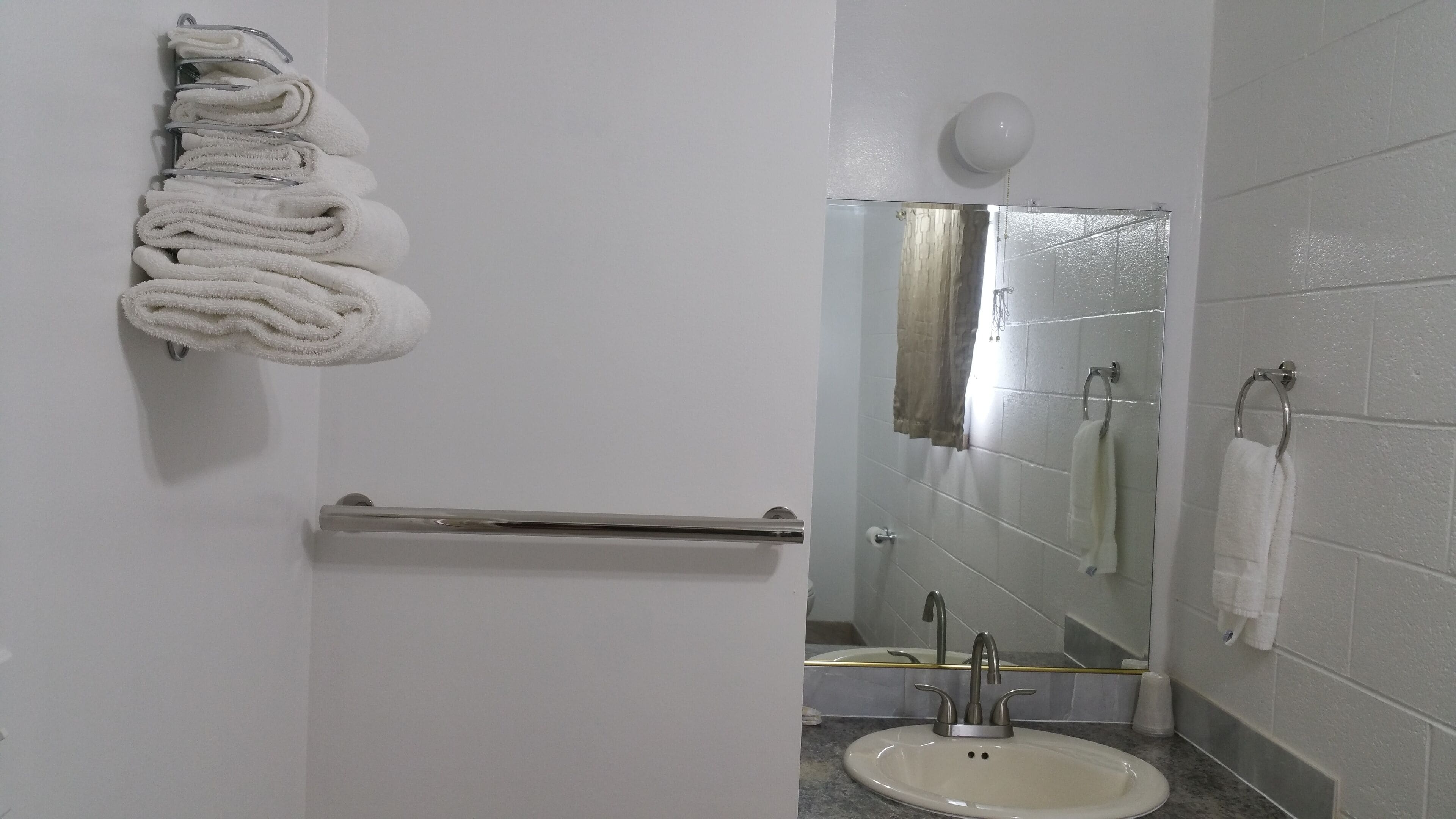 A bathroom with a white sink, a towel rack, a mirror, and a shower area.