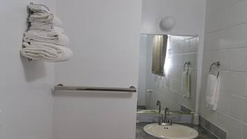 A bathroom with a white sink, a towel rack, a mirror, and a shower area.