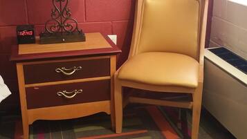 Quarto com parede de tijolos vermelhos, mesa de cabeceira de madeira com abajur, cadeira e relógio.