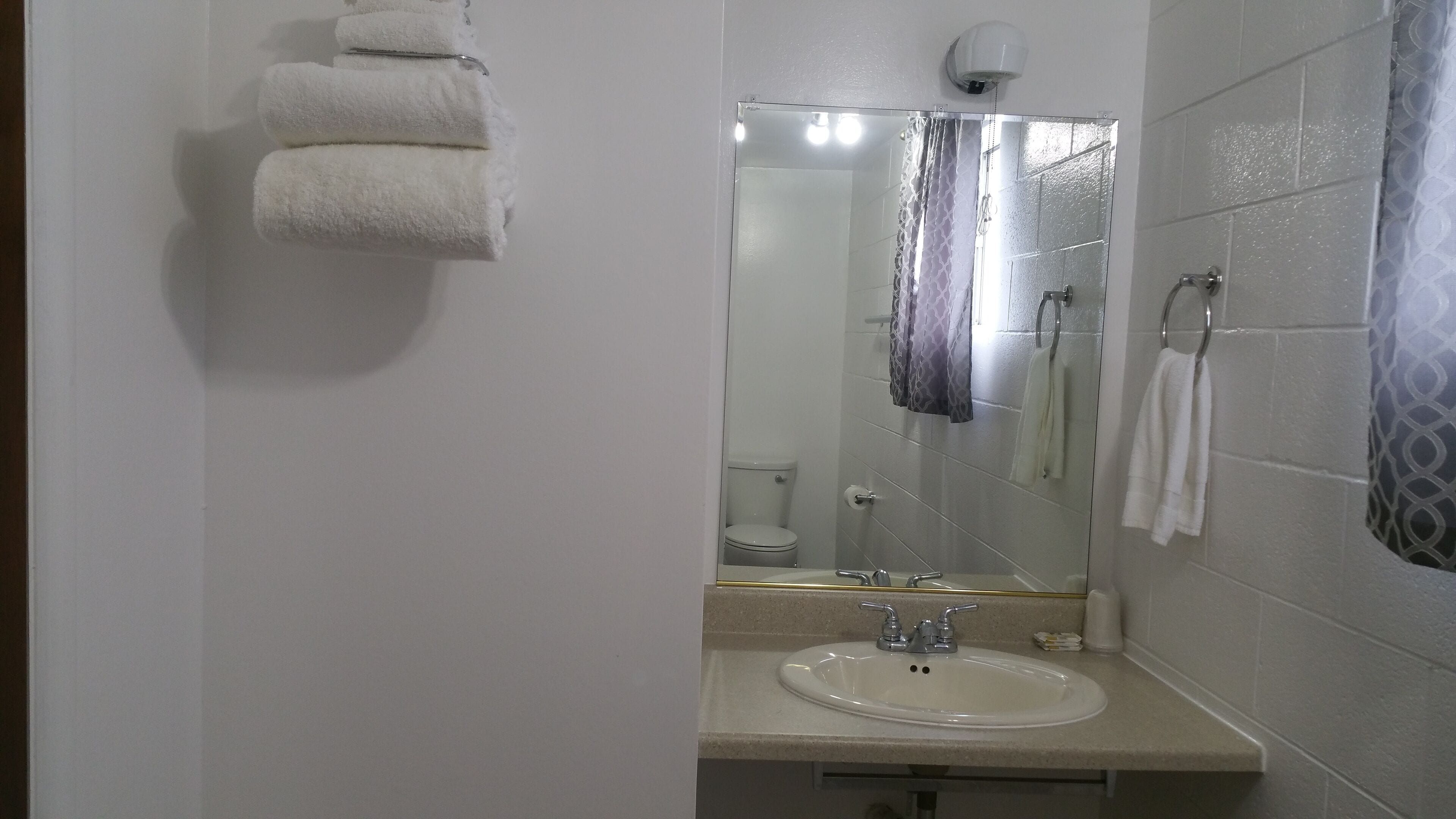 A bathroom with a sink, mirror, and towel rack.