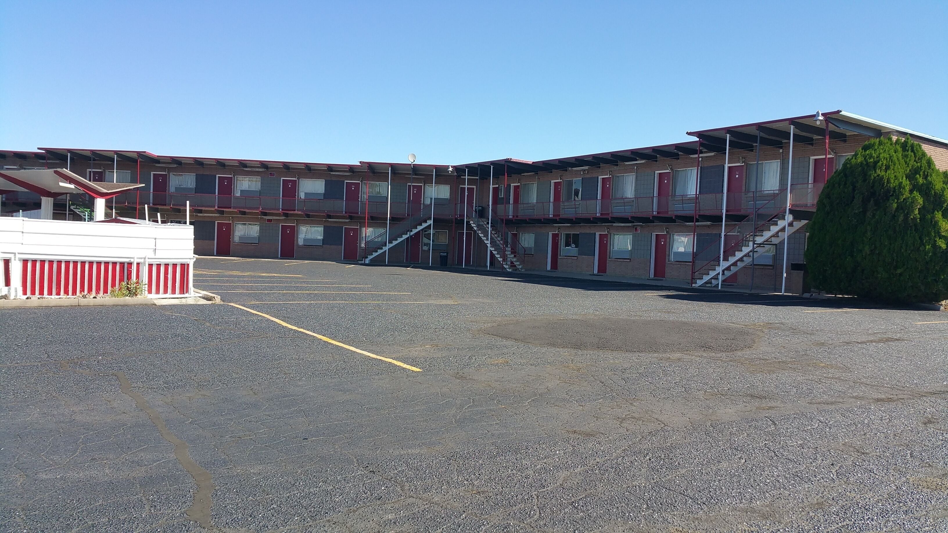 Un motel de varios pisos con un estacionamiento al frente.