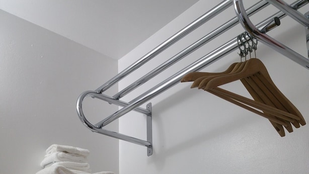 A bathroom with a metal towel rack and wooden hangers. - Thunder Bird Motel (Mountain Home)