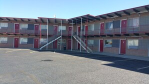 A multi-story motel with a central staircase, individual rooms numbered on the exterior, and a parking lot in front. - Thunder Bird Motel (Mountain Home)