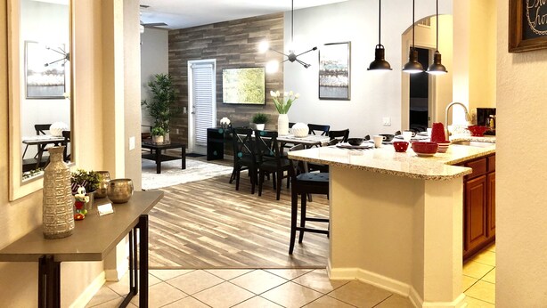 A modern kitchen with a central island, dining area with chairs, and a living space with a fireplace.