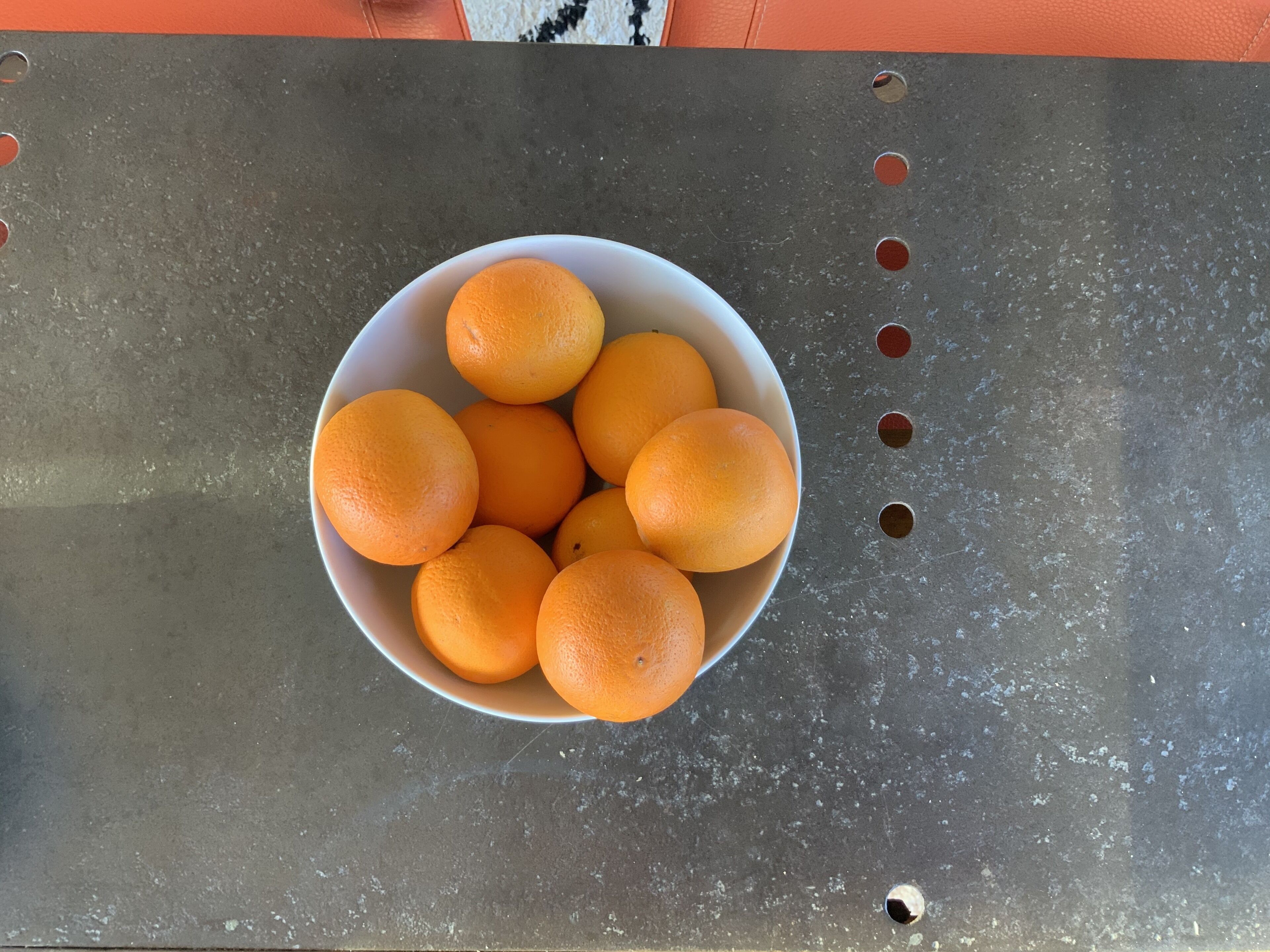 Un bol d’oranges posé sur une surface métallique.